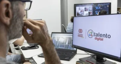 Un hombre con gafas mirando a la pantalla de un ordenador donde sale el logo de por talento digital y fundación once