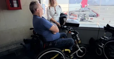 hombre en silla de reudas observando un avión desde una ventana