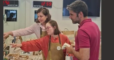 Dos profesores atendiendo a una alumna del CEE ACHIRA, enseñándola a vender en el mercadillo