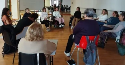 Las mujeres participantes del programa reunidas en una sala con todas sentadas haciendo un círculo para hablar