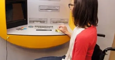 Una persona en silla de ruedas en un cajero automático accesible, al dar luz verde al proyecto de ley para adaptarlos junto al 112 y otros servicios (Fuente: Discapnet)