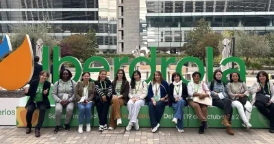 Doce mujeres que formaron parte del programa sentadas delante del logo de Iberdrola en sus oficinas centrales