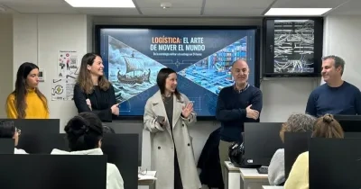 Varios formadores del taller impartiendo indicaciones frente a los alumnos, con el proyector de fondo presentando una diapositiva