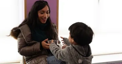 niño con TEA cogiendo un cuenco de la mano de su madre