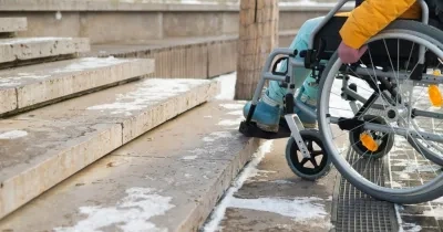 Persona con silla de ruedas ante unas escaleras
