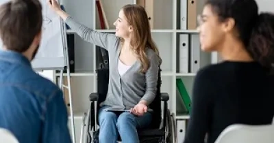 Una persona con discapacidad y en silla de ruedas, en una reunión de trabajo (Fuente: Servimedia)