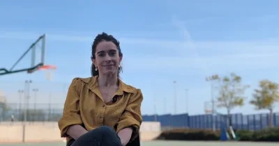 Una de las impulsoras del estudio, posando a cámara sentada en una pista de atletismo y baloncesto de fondo.