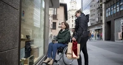 Persona en silla de ruedas mirando el escaparate de una tienda (Fuente: Predif)