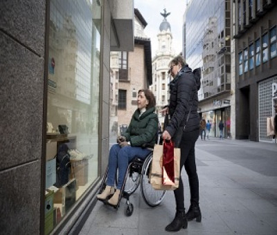 Persona en silla de ruedas mirando el escaparate de una tienda (Fuente: Predif)