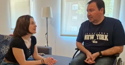 Una mujer sentada en un sofá hablando con una persona en silla de ruedas