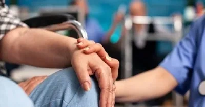 Un asistente sanitario reconforta a una persona sentada en una silla (Fuente: Servimedia)