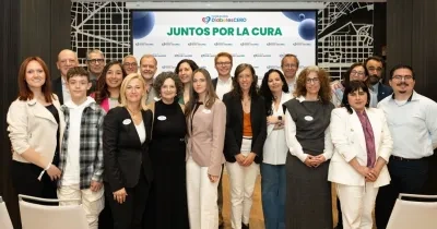 Veinte personas posando para la foto junto delante de la pantalla digital donde se proyectan diapositivas del encuentro