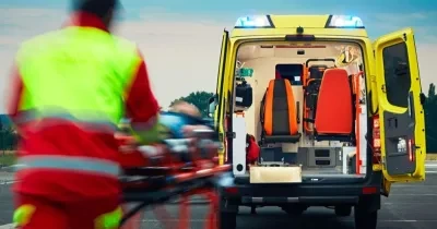 Un profesional del servicio de emergencias traslada a un paciente en camilla hasta una ambulancia