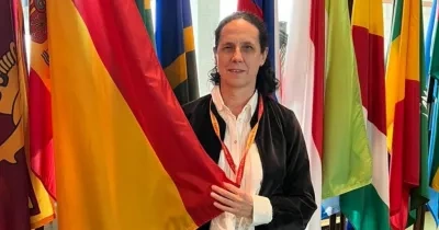 Ana Peláez sosteniendo la bandera de España al lado del resto de banderas mundiales