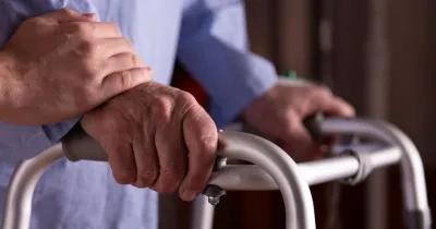 Primer plano de las manos de un hombre mayor sosteniendo un andador