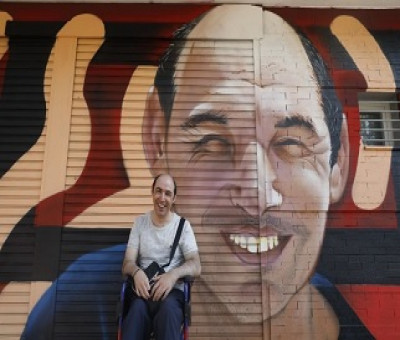 Uno de los usuarios de la Oficina de Vida Independiente frente a una de las obras del artista David Barrera en las fachadas de este centro (Fuente: Twitter Pepe Aniorte)