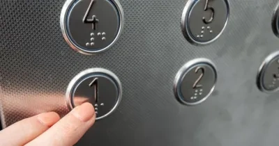 dedos de una persona pulsando botones de un ascensor con el número también en formato braille
