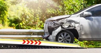 vehículo con un golpe en el frontal de un coche subiéndose a una rampa de una grúa