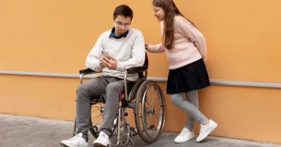 chico en silla de ruedas con discapacidad enseñando algo de su móvil a una chica