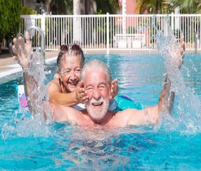 Dos personas disfrutando de una piscina mientras una tapa los oídos a otra (Fuente: Oticon)