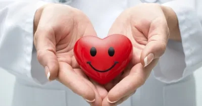 medico sosteniendo un corazón de juguete con una sonrisa dibujada