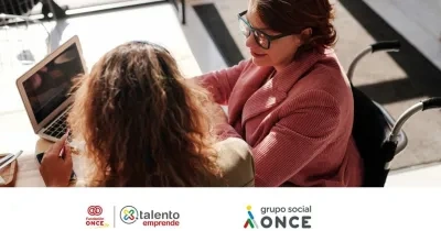 Dos mujeres, una con discapacidad, mirando a la pantalla del ordenador mientras trabajan