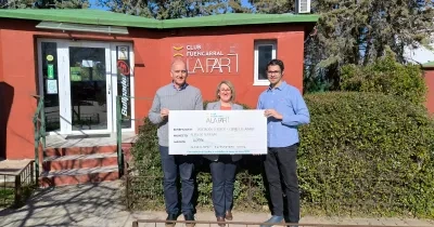 Tres personas posan frente a la sede del Club Fuencarral A LA PAR sosteniendo un cheque simbólico de ayuda económica para un proyecto deportivo dirigido a personas con discapacidad intelectual. Al fondo se ve el edificio del club y su rótulo identificativo.