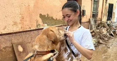 Una mujer con un perro en Valencia con el barro provocado por la Dana en Valencia