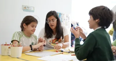 Imagen de Autismo España sobre educación inclusiva en el que aparece una profesora en clase con alumnado con discapacidad