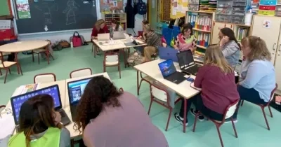 Ocho profesoras mirando ordenadores en un aula infantil