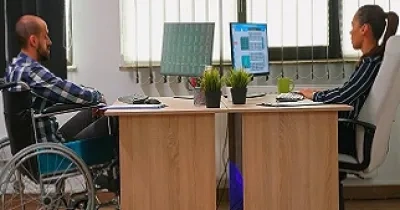 Una persona en silla de ruedas trabaja en una oficina junto a otra compañera (Fuente: Servimedia)