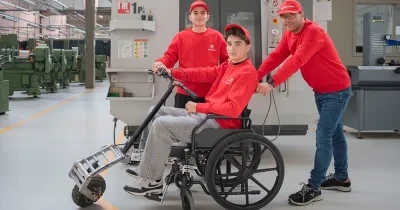 En la imagen se puede ver a los dos alumnos y al profesor, uno de ellos probando el proyecto en una silla de ruedas