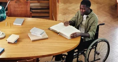 estudiante con silla de ruedas en una biblioteca estudiando