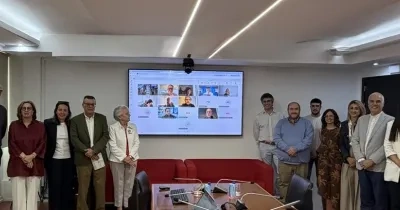 Participantes del grupo de la reunión con una pantalla digital en la que estaban proyectando una sesión virtual con otros participantes