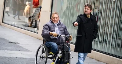 Un asistente personal al lado de un hombre en silla de ruedas