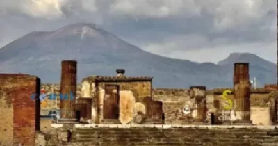 Unas ruinas históricas delante y unas montañas con nubes detrás, que son parte de la portada de la guía