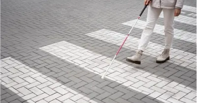 hombre con discapacidad visual andando por un paso de cebra con el baston