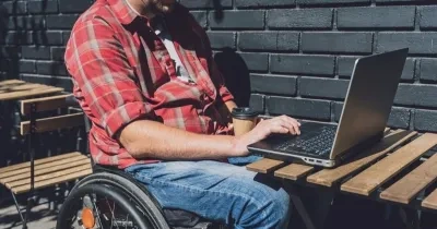 persona en silla de ruedas con discapacidad usando el portátil