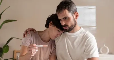 una pareja de hombre y mujer visionando un test de embarazo, simbolizando la tristeza de un resultado negativo