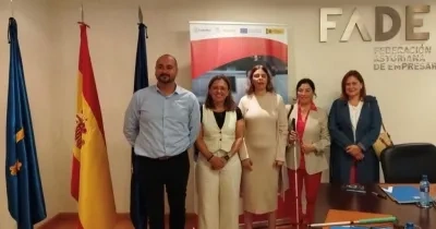 representantes de ambas entidades posando tras la firma del acuerdo con las banderas de la Unión Europea, España y Asturias de fondo