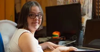 Joven con Síndrome de Down estudiando con su pórtatil