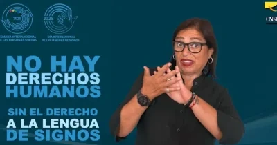 Imagen de una mujer con gafas y camisa negra haciendo un gesto con las manos, sobre un fondo azul con logotipos de la Semana de Personas Sordas 2025 y CNSE. Texto: "NO HAY DERECHOS HUMANOS SIN EL DERECHO A LA LENGUA DE SIGNOS".