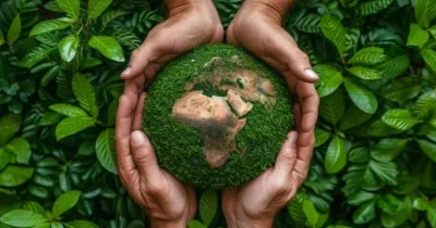 manos sosteniendo el mundo con plantas verde de fondo