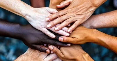 varias manos unidas en el centro, recreando la cohesión grupal. Además, las manos son de personas con diferentes razas, lo que significa la unión mundial