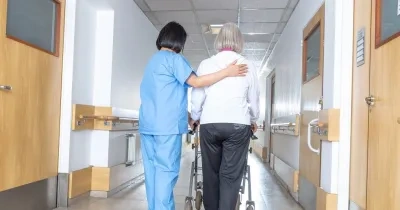 médico andando con una persona mayor por pasillos de una residencia