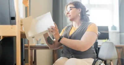Una mujer en silla de ruedas revisa unos documentos en una oficina