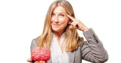 mujer llevando un dedo a la sien y con la otra mano sosteniendo un cerebro de juguete