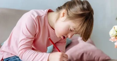 Niña con síndrome de down pintando un dibujo en un cuaderno