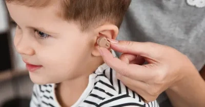 mujer poniendo un audífono a un niño pequeño