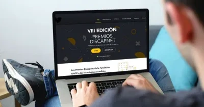 hombre sosteniendo un ordenador portátil con la pantalla encendida en la web oficial de los Premios Discapnet